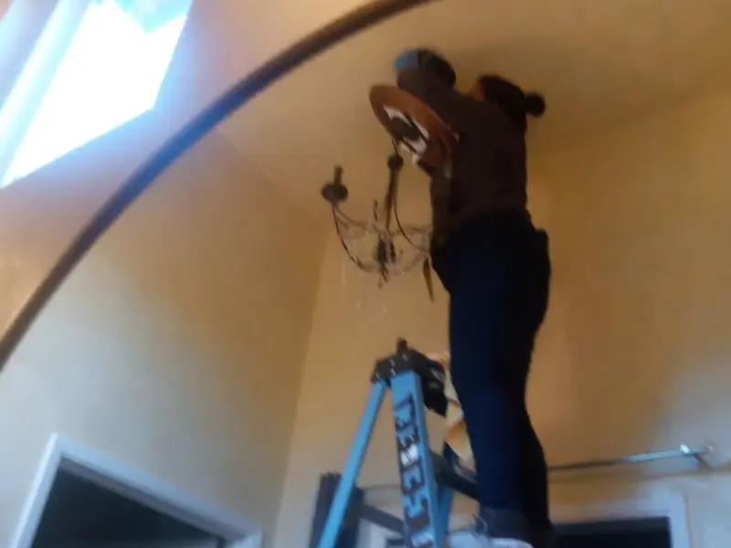 Electrician installing a chandelier in a Ashford residence